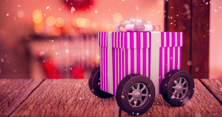 Gift on wheels against pine cone decoration on fake snowの写真素材