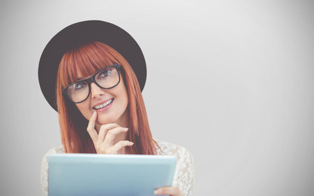 Smiling hipster woman using her tablet against white background with vignetteの写真素材