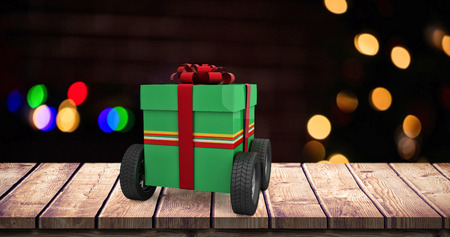 Green gift box with wheels against pine cones decoration on fake snowの写真素材