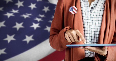 Businesswoman using a tablet against close up of the us flag