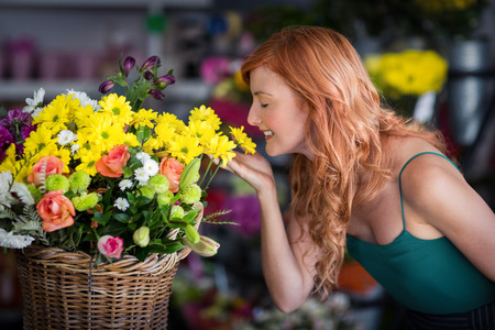 Smiling female florist smelling flowers at flower shop