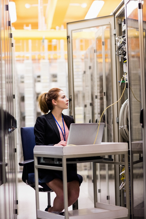Technician using laptop while analyzing server in server room
