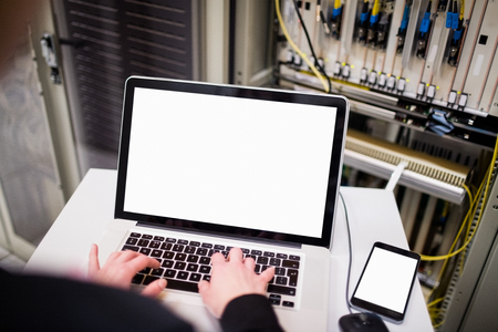 Technician using laptop while analyzing server in server room
