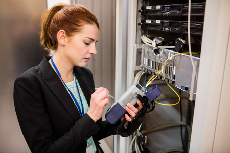 Technician using digital cable analyzer in server roomの写真素材