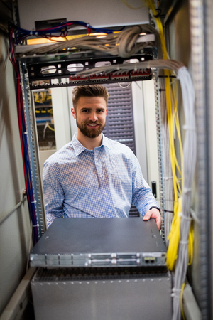 Portrait of technician removing server from rack mounted server in server room