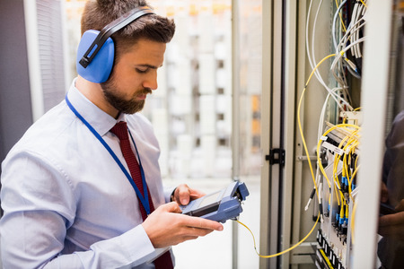 Technician using digital cable analyzer in server roomの写真素材