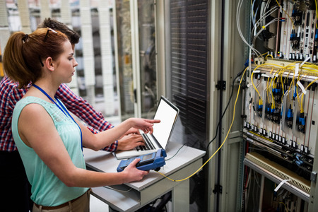 Technicians using laptop while analyzing server in server roomの写真素材