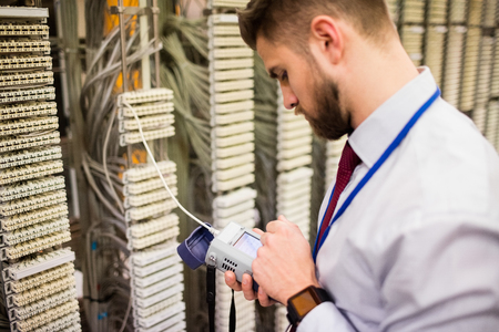 Technician using digital cable analyzer in server room