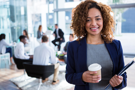 Portrait of smiling businesswoman holding coffee in officeの写真素材