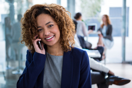 Portrait of smiling businesswoman talking on mobile phone in officeの写真素材