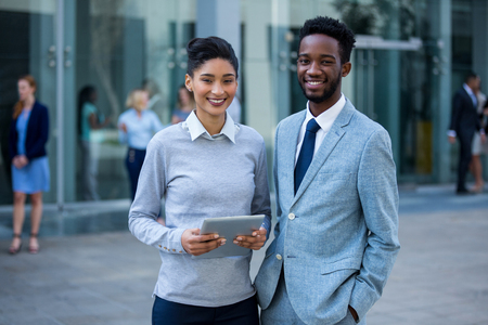 Portrait of businessman and colleague holding digital tablet in office buildingの写真素材