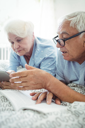 Senior couple interacting with each other on bed at bedroomの写真素材