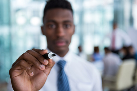 Businessman writing with marker on glass in officeの写真素材