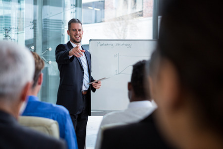 Businessman interacting with co-worker while discussing on white boardの写真素材