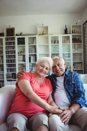 Portrait of senior couple sitting together on sofa at homeの写真素材