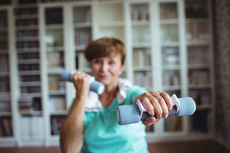 Senior woman exercising with dumbbells at homeの写真素材