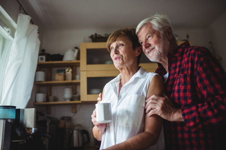 Senior couple standing in kitchen at homeの写真素材