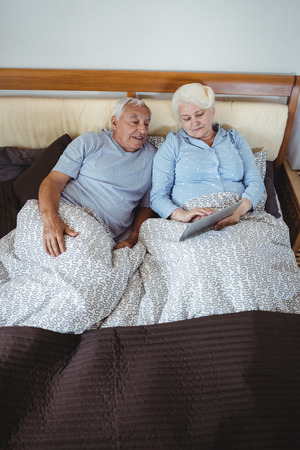 Senior couple using digital tablet in bedroomの写真素材