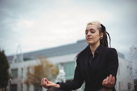 Businesswoman practicing yoga in office campusの写真素材