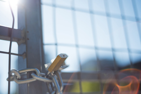 Close-up of fence locked with chain and padlockの写真素材