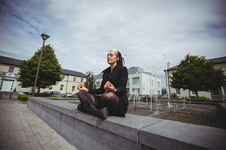 Businesswoman practicing yoga in office campusの写真素材