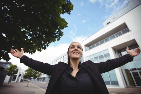 Businesswoman standing with arms outstretched in office campusの写真素材