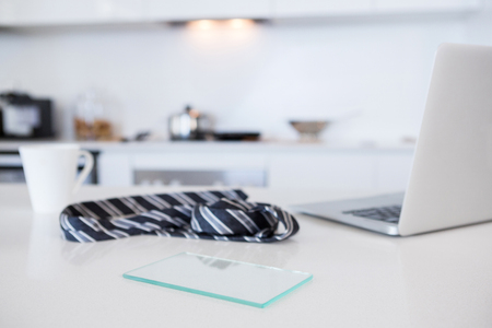 Tie with coffee mug and laptop in kitchen at homeの写真素材