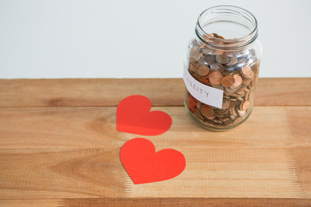 Close-up of coins in bottle and heart on tableの写真素材