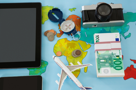 Electronic gadgets, camera, dollar, compass, and airplane model on tableの写真素材