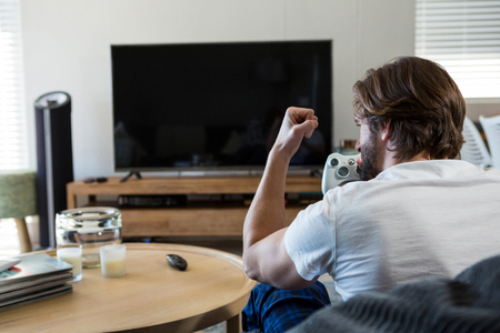 Man playing video games in living room at homeの写真素材