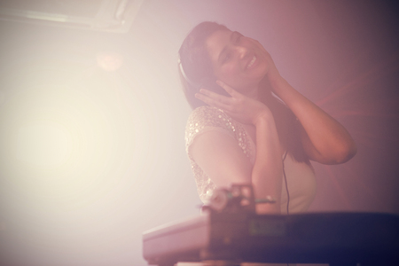 Pretty female DJ playing music at the nightclub