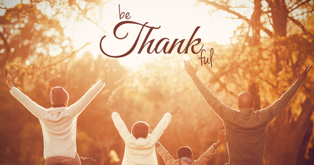Digital image of happy thanksgiving day text greeting against rear view of a young family with arms raised on bikeの写真素材