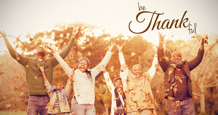 Digital image of happy thanksgiving day text greeting against happy family throwing leaves aroundの写真素材