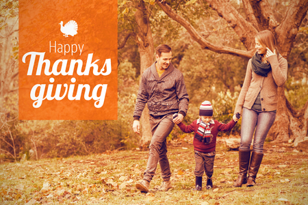 Thanksgiving greeting text against smiling young family walking togetherの写真素材