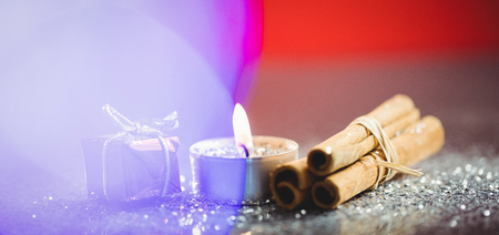 Cinnamon stick, lit candle and gift during christmas timeの写真素材