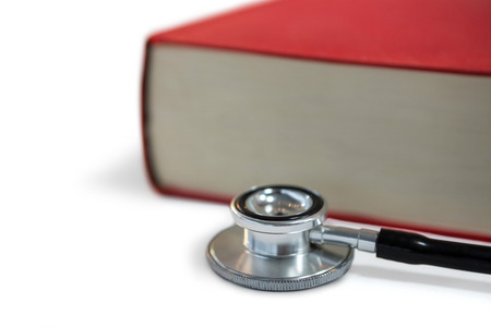 Close-up of stethoscope with book on white backgroundの写真素材
