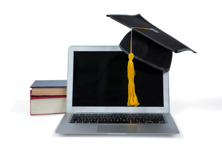 Laptop with mortarboard and books on white backgroundの写真素材