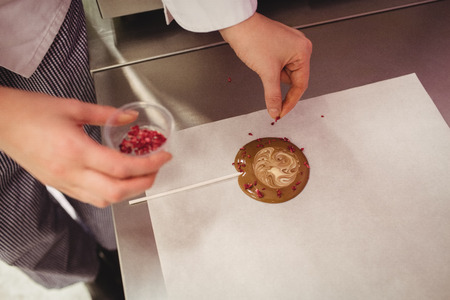 Worker preparing lollipop on wax paper in kitchenの写真素材