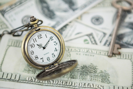 Close-up of pocket clock on one hundred dollar billsの写真素材