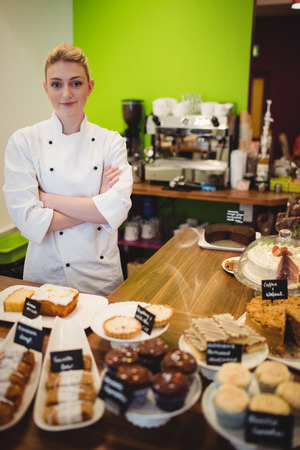 Portrait of worker standing at chocolate counter in cake shopの写真素材