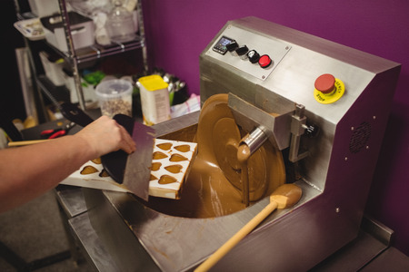 Worker filling mould with melted chocolate in kitchenの写真素材