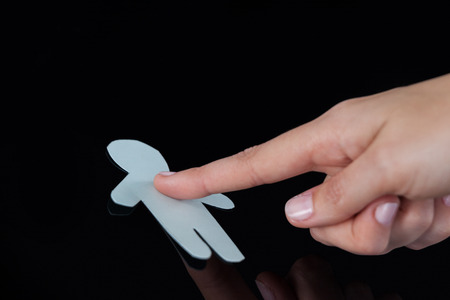 Close-up of woman hand touching human paper cut out on a glassの写真素材