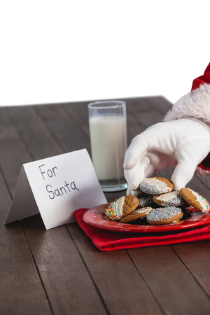 Close-up of santa claus taking cookies on white backgroundの写真素材