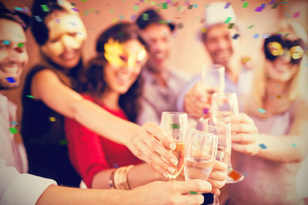 Cropped image of hands holding champagne flute against flying coloursの写真素材