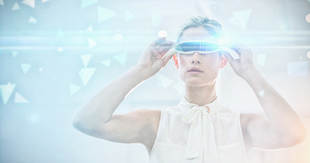 Technical screen with little pyramids against businesswoman holding virtual reality simulatorの写真素材