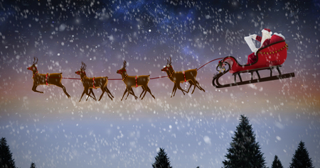 Side view of Santa Claus riding on sleigh during Christmas against snow falling on fir tree forestの写真素材