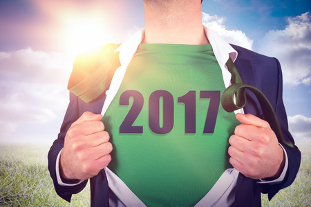 Businessman opening shirt in superhero style against sunny landscape