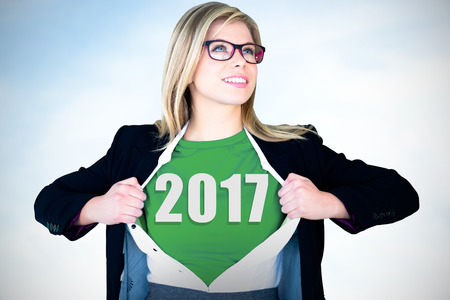 Businesswoman opening shirt in superhero style against blue sky