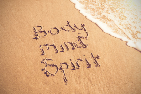 Body mind spirit text written on sand with surf at beachの写真素材