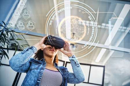 Digitally generated  image of globe with big data text against low angle view of businesswoman enjoying virtual reality headset at officeの写真素材